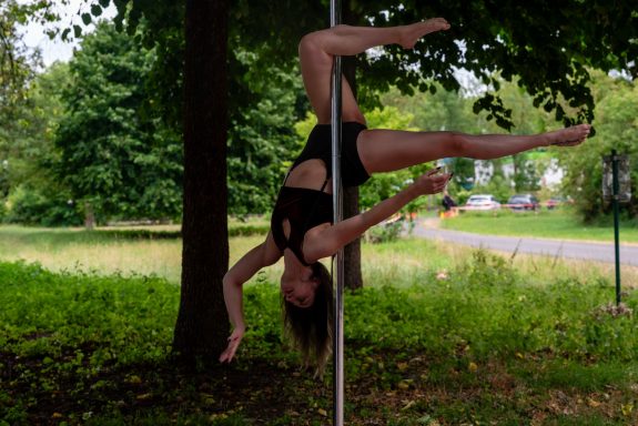 Eine Tänzerin macht eine akrobatische Bewegung an einer Pole in der Natur.