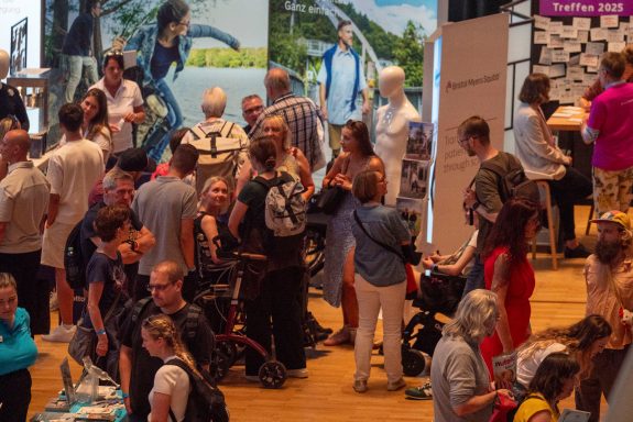 Menschenmenge auf einer Veranstaltung, einige interagieren, andere schauen Ausstellungen an.