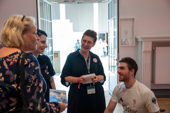 Eine Gruppe von vier Personen im Gespräch, darunter ein junger Mann und zwei Frauen.